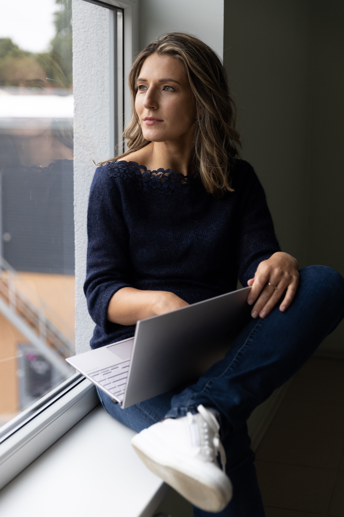 Aija Hermane-Sabule seated beside a window with a laptop